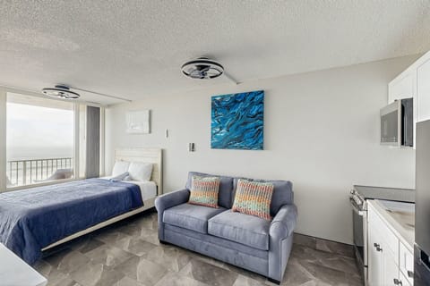 Bright beachfront studio featuring a cozy bed, sleeper sofa, and modern kitchenette. Enjoy ocean views, coastal décor, and an open layout—perfect for a relaxing beach stay just steps from the shore.