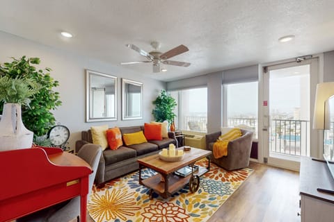 Sunlit living room with cozy seating, vibrant décor, and balcony access overlooking the coast. Relax after a beach day in this inviting beach stay, perfect for unwinding, entertaining, and enjoying seaside vacation comfort.