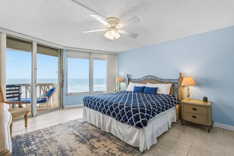 Serene oceanfront bedroom featuring a plush king bed, coastal décor, and sliding doors to a private balcony. Wake up to soothing waves and sea views during your relaxing beach stay.