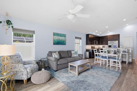 Inviting open living space with beach-inspired décor, comfortable seating, and a dining area that flows into a modern kitchen. Perfect for relaxing and gathering with family during your coastal beach stay getaway.