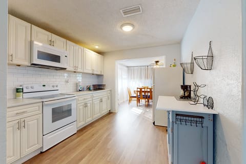 Cook and gather in this bright beach stay kitchen featuring modern appliances, ample counter space, and a light coastal design. The open layout flows into the dining area—ideal for meals after a relaxing day at the beach.