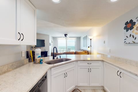 This bright beach stay kitchen offers spacious countertops, white cabinetry, and a seamless view into the oceanfront living area—perfect for cooking, relaxing, and enjoying coastal comfort.
