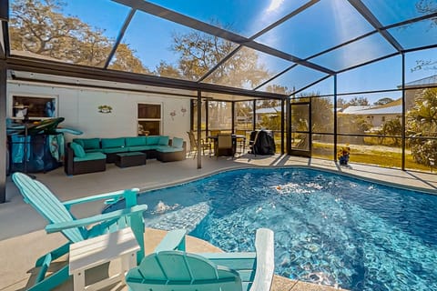 Enjoy this bright, beach-inspired pool area with comfy seating, dining space, and a sparkling screened-in pool—perfect for relaxing, entertaining, and soaking up the sunshine during your beach stay.