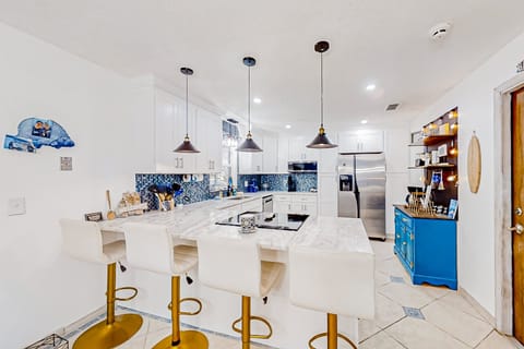 Enjoy this fresh, beach-inspired kitchen featuring marble counters, modern appliances, and a spacious breakfast bar—perfect for cooking, gathering, and unwinding after a relaxing beach stay.