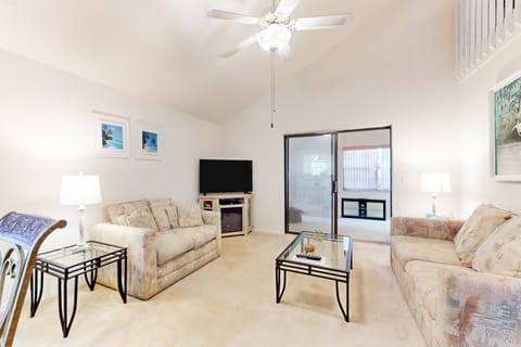 Relax in this airy, beach-inspired living room featuring cozy sofas, coastal décor, and a large TV. Perfect for unwinding after a sunny beach day in your comfortable vacation retreat.