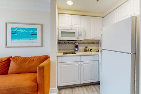 Fresh white kitchenette with full fridge, cooktop, and microwave—perfect for easy beach-stay meals. Enjoy ocean vibes just steps from the shore in this sunny, inviting space.
