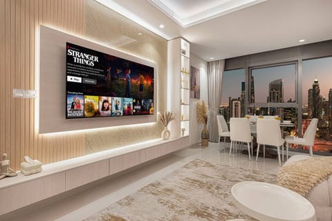 Open Living and Dining Area with a backlit feature wall,  large smart  TV , elegant  dining set , and breathtaking city skyline views at dusk.