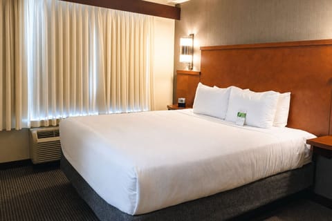 Unwind in a serene king bed with warm bedside lighting.