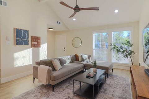 Open-concept living, dining, and kitchen area — bright, airy, and perfect for relaxing or entertaining.  Living room features Crate & Barrel media console, 75-inch smart TV with Bose soundbar, and West Elm couch with ottoman.