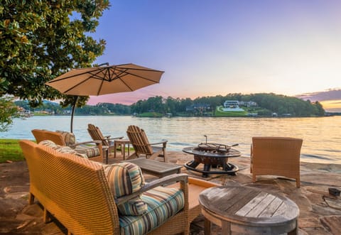 Unwind at sunset in comfy outdoor seating with fire pit and stunning lakefront views.