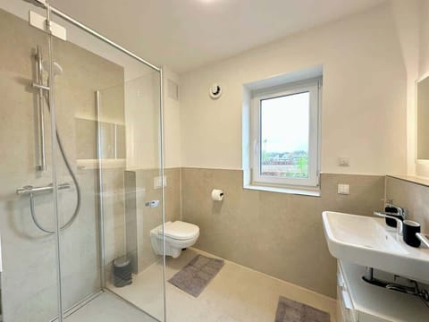 Tageslichtbad mit bodentiefer Dusche, Toilette, Waschtrockner Föhn, Seife, Shampoo, Toilettenpapier und frischen Handtüchern.
Um das Fenster abzudunkeln, gibt es elektrische Rollläden.