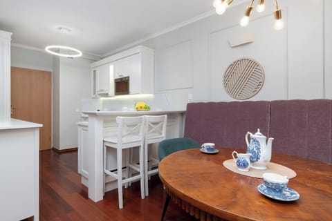 A small dining nook featuring a round wooden table and a bench, perfect for casual meals. The area is connected to a bright and airy living space.