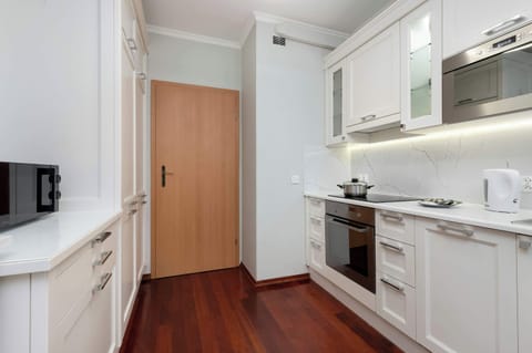 A sleek white kitchen with a countertop for meals and a dining area nearby. Clean lines and modern appliances make it functional and stylish.