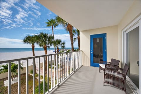 Sunny outdoor walkway w/ palm-lined water views and a pop of color from the bright blue door.