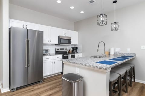 Brightly stocked kitchen with all major appliances, a dishwasher, and a large island with seating for four.