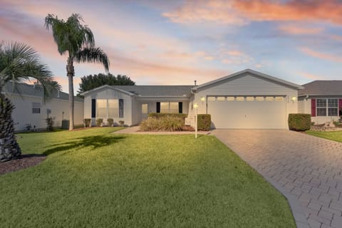 Charming single-story home with manicured lawn and tropical palm trees, perfectly positioned in a quiet residential neighborhood for peaceful Florida living.