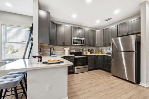 This stylish kitchen boasts a durable tile backsplash, deep sink, quality appliances, and warm wood flooring.