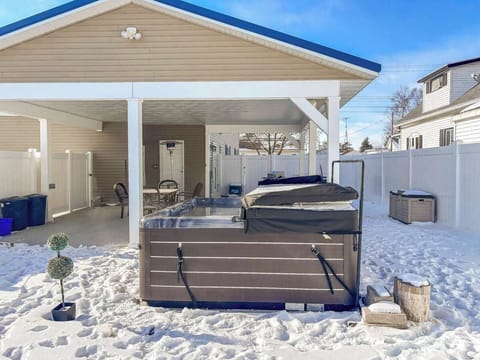 Backyard view showcasing the steaming hot tub and cozy outdoor seating area with a heater. Perfect for relaxing, warming up, and enjoying the fresh air in comfort, no matter the season.