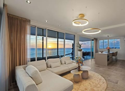 Unwind in the spacious, open-plan living area. Floor-to-ceiling glass doors open to the balcony, filling the room with natural light and offering stunning ocean views.