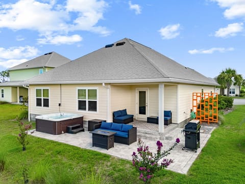 Spacious backyard patio featuring a private hot tub, comfortable outdoor seating, and a grill for entertaining guests.