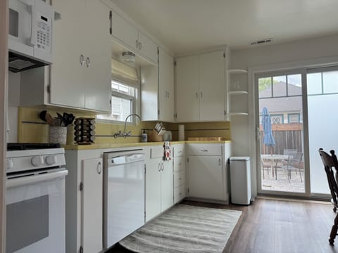 Well-lit kitchen with original tile countertops and cabinetry.