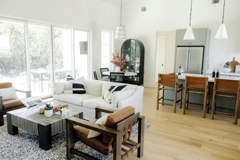 Sunlit living room with leather chairs, patio access, and chic dining
