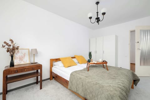 A bedroom with a double bed, warm yellow cushions, and a wooden side table. The angled ceiling adds character to the space.