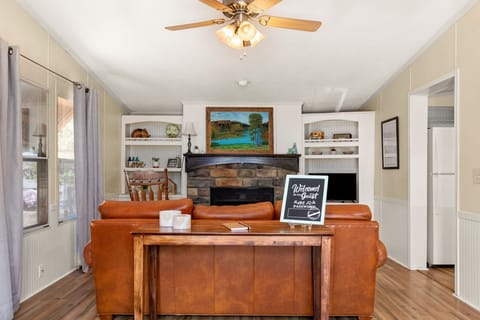 This bright, open living room features a stone fireplace, built-in shelving, and cozy seating. A comfortable place to relax after work or enjoy quiet mornings.