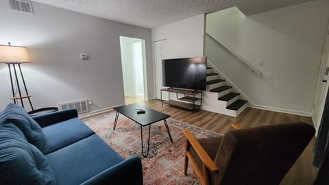 Living Room: The living room features a 55” flatscreen TV and a cozy couch, providing the perfect spot to keep you entertained after a long day out.