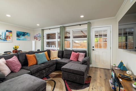 Bright, cozy living room with a large sectional, a smart TV, board games & DVDs