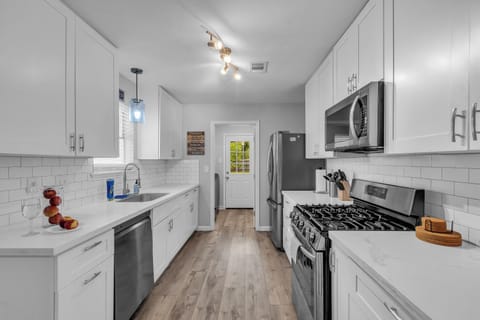 Stainless kitchen with appliances, coffee station, and cookware for guest use.