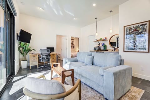 The living area combines comfortable seating, a mounted TV, and a dedicated desk setup, all oriented toward the expansive scenery outside.