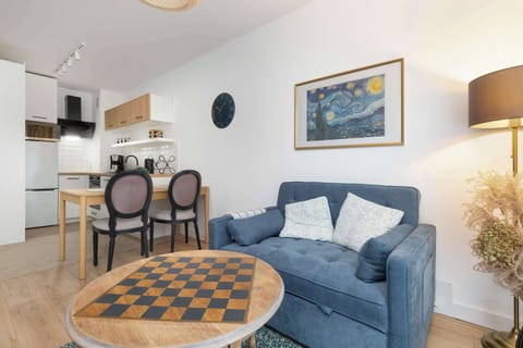 The living and dining space with a small chessboard on the coffee table and chairs around the dining table. The room feels airy and modern.