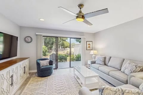 Bright living room with modern furnishings and sliding glass doors opening to a garden view.