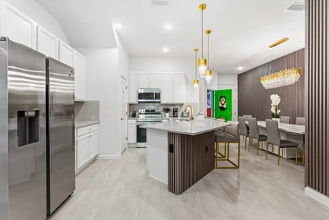 Enjoy a bright kitchen with sleek white cabinetry and gold accents for a fresh vibe. The spacious island invites casual dining, while the elegant dining area with chic gray chairs sets the scene for memorable meals.