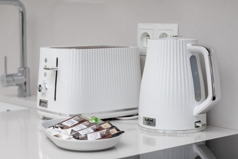 Practical kitchen corner with kettle, cups, and stove.