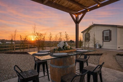 Outdoor dining table with place settings on a barrel base at dusk.
