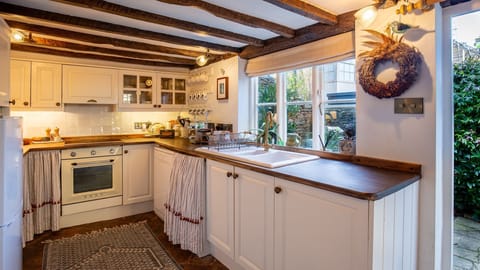 Curtains cover the washing machine, exposed beams are above and you stand on a tiled floor.