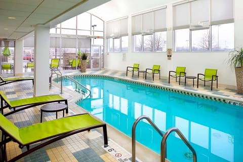 Bright indoor pool with green lounge chairs and seating