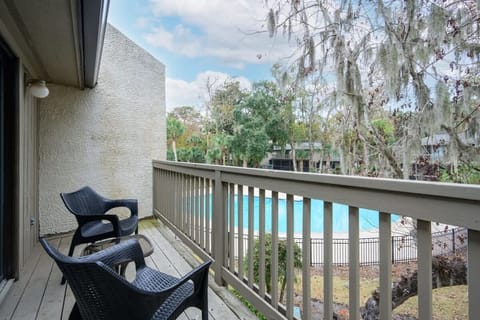 Shaded tiki bar with colorful seating overlooks a sunny resort lazy river.