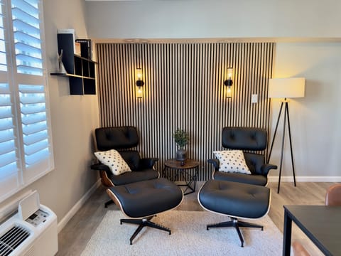 Bright and cozy living room with modern leather lounge chairs, large windows with shutters, stylish decor and a sleek floor lamp, ideal for relaxing after exploring Cape May or streaming your favorite shows.