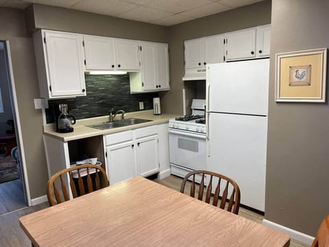 Kitchen with fridge, stove, coffee maker, pots and skillets and utensils. 