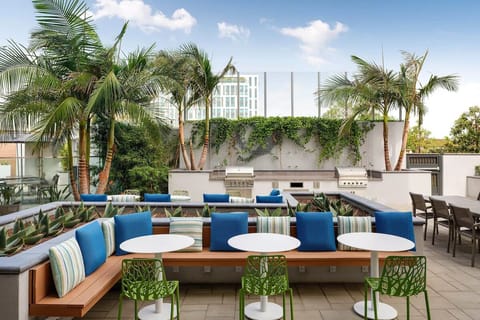 Gather outdoors with cozy seating and grills under palms.