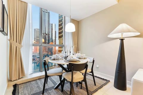 Cozy dining area featuring a comfortable four-seater table next to a large window with stunning lake views, seamlessly connected to the living area for a spacious and inviting layout.