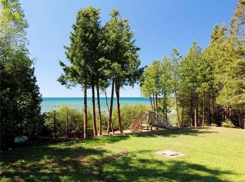 Private waterfront setting with a spacious grassy yard, mature trees, and direct access to the clear waters of Lake Huron.