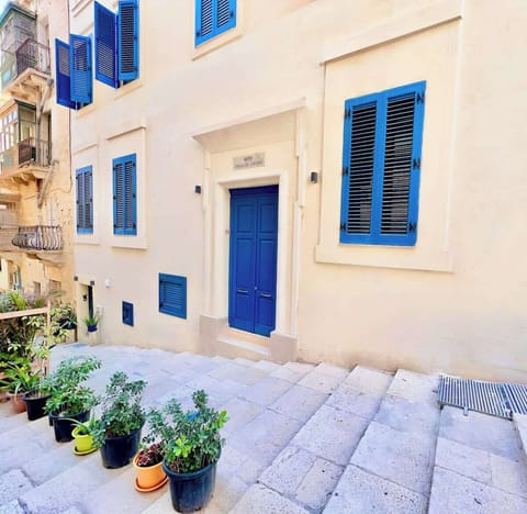 Your home for the stay: a traditional Valletta streetscape with limestone walls and classic blue shutters.