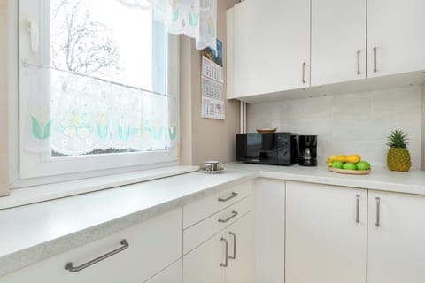 A clean white kitchen layout featuring upper cabinets, a countertop appliance set, and under-cabinet lighting.