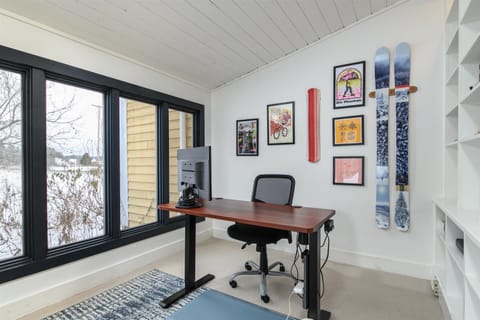 Your private workspace features a comfortable desk setup, complete with computer monitor with natural light, perfect for remote work or planning your mountain adventures.