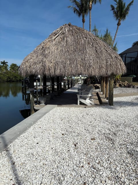 Cozy tiki hut with thatched roof, warm lighting, and tropical vibes by the shore