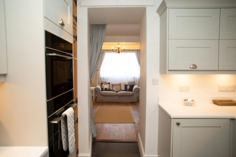 Kitchen detail of oven and microwave, fitted units, view into living room with sofa